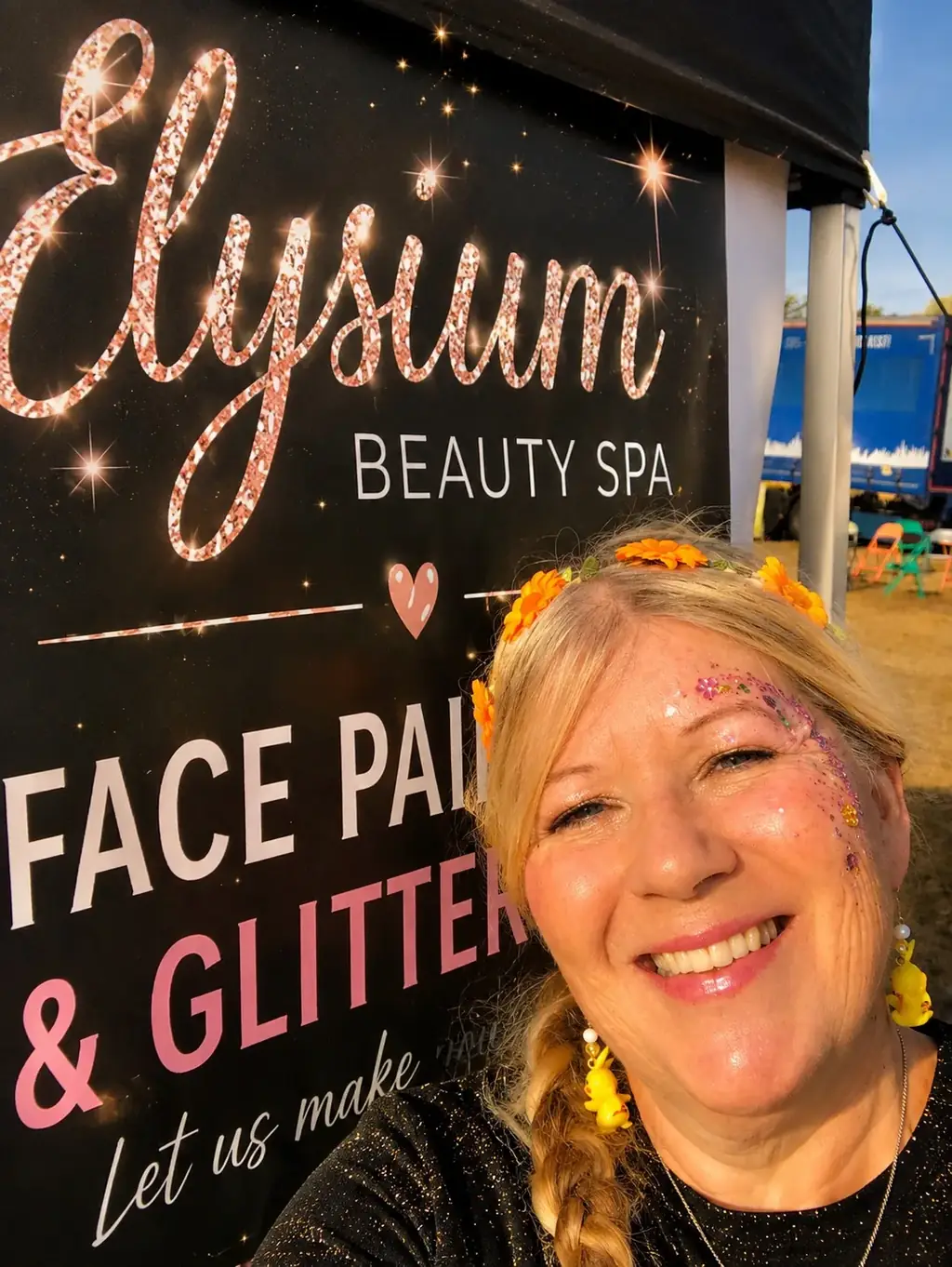One of the Glitter Sisters with glitter face art at an outdoor event